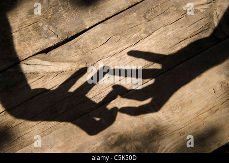 Männliche Hände werfen Schatten auf Holztisch Stockfoto