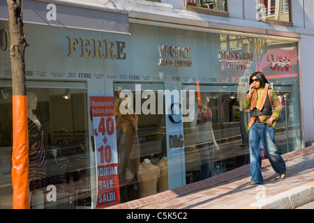 Junge Frau zu Fuß auf dem Bürgersteig und telefonieren mit Handy in Nisantasi, Istanbul, Türkei Stockfoto