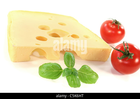ein Stück Schweizer Käse mit Tomaten und Basilikum auf weißem Hintergrund Stockfoto