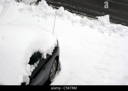 Ein Fahrzeug mit Schnee bedeckt und eingeschneit, kurz nach der Stadt Pflug die Einfahrt übergeben. Stockfoto