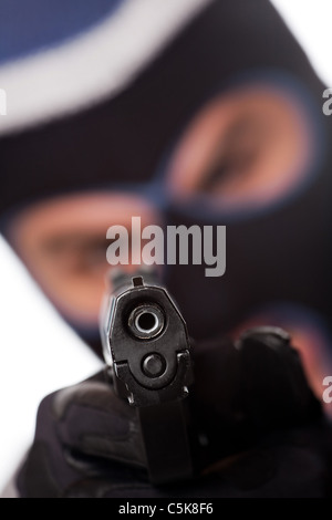 Ein verärgerter aussehende Mann trägt einen Ski-Maske zeigt eine schwarze Pistole auf den Betrachter. Geringe Schärfentiefe. Stockfoto