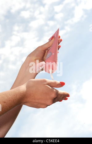 Junge Frau auspressen Handcreme auf ihre Handflächen gegen Himmel Stockfoto