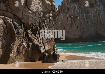 Mann auf einer riesigen Felswand in der Nähe von Pazifischen Ozean entlang krabbeln. Stockfoto