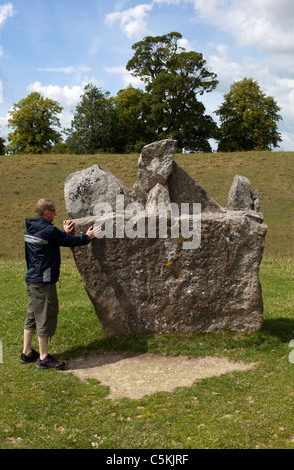 Mann berühren einen Stein bei Avebury Stone Circle Wiltshire Stockfoto