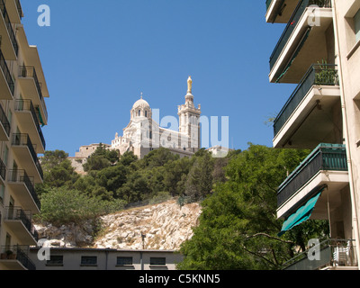 Kirche von Notre-Dame-de-la-Garde, Marseille, Frankreich, zwischen Wohnblocks von unten gesehen Stockfoto