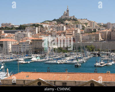 Hafen von Marseille, Frankreich, mit Yachthafen, umgeben von Häusern und Wohnblocks, Kirche von Notre-Dame-de-la-Garde auf Stockfoto