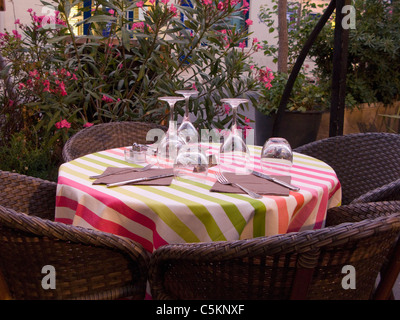 Ein Restaurant im freien Tisch gedeckt mit gestreiften Tischdecken, Besteck und Gläser und 4 Stroh Stühle, Arles, Frankreich Stockfoto