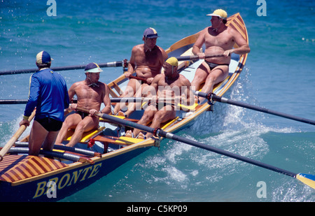 Surf Lifesaving Boot mit fünf Männern unterwegs über eine Welle am Bondi Beach, Sydney, Australien Stockfoto