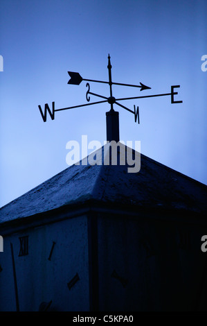 Ein Wetterhahn auf dem Dach ein Gebäude, nach Nord-Ost, Silhoutted vor einem blauen Himmel Stockfoto