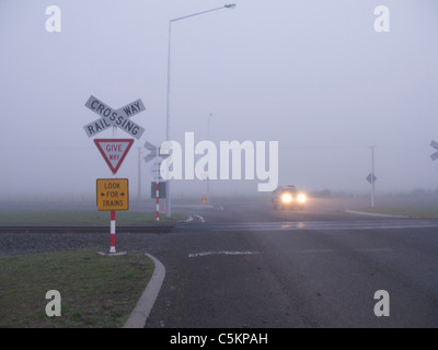 Bahnübergang in Nebel, mit Zeichen und einem Auto überquert die Bahn verfolgt, Dunsandel, Canterbury, Neuseeland Stockfoto