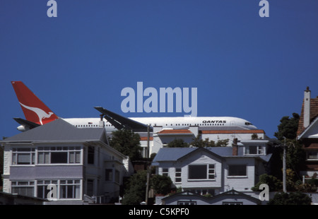 Boeing 767 Verkehrsflugzeug von Qantas Airways kommen, um in Wellington, New Zealand, Tiefflug über Häuser auf einem Hügel in der Nähe landen die Stockfoto