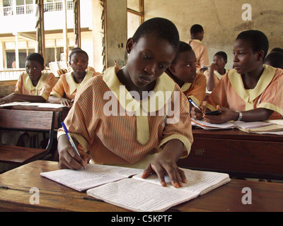 Lagos, Nigeria: Teenage Studentin sitzt an einem Schreibtisch in einem Klassenzimmer einer öffentlichen Schule. Schüler tragen eine Uniform. Stockfoto