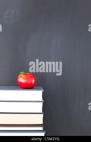 Ein roter Apfel auf einem Stapel von Büchern und eine saubere Tafel Stockfoto