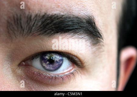 Nahaufnahme von einem mans Auge und Augenbraue mit der Erde in seiner Iris überlagert. Stockfoto