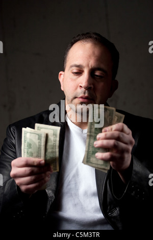 Ein Mann mittleren Alters, eine Handvoll von hundert-Dollar-Scheine zu zählen. Geringe Schärfentiefe mit Fokus auf das Gesicht. Stockfoto