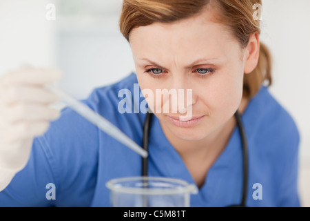 Junge Wissenschaftlerin Vorbereitung ein Experiment mit einer Pipette und einen Becher Stockfoto