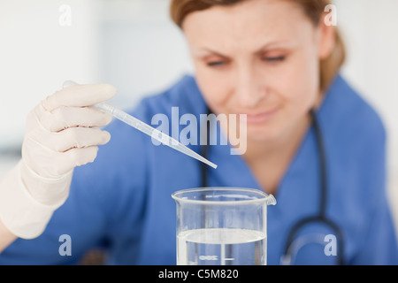 Blonden Wissenschaftler Vorbereitung ein Experiment mit einer Pipette und einen Becher Stockfoto
