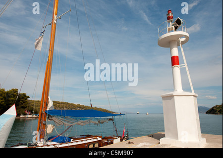 Helle Leuchtfeuer und Segelboot im griechischen Hafen Nea Epidavros Stockfoto