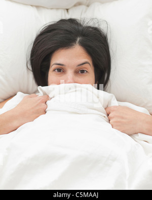 Hispanic Frau im Bett für ihr Gesicht Stockfoto