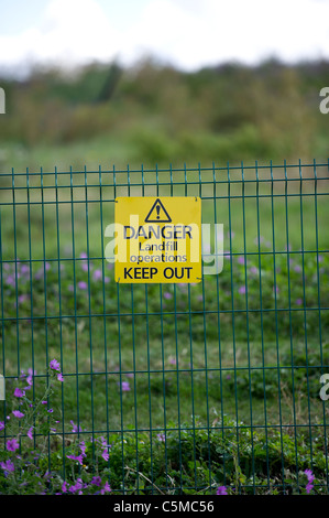 Ein Teil der grünen Stahl Sicherheitszaun mit einer "Gefahr, Deponie-Operationen, Keep Out"-Zeichen. Stockfoto