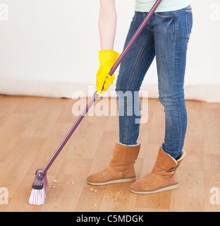 Attraktive rothaarige Frau fegt den Boden zu Hause Stockfoto