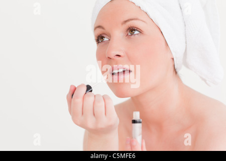 Hübsche junge Frau trägt ein Handtuch mit einem Lipgloss Stockfoto