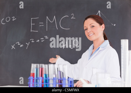 Niedliche Wissenschaftler zeigen die Gleichungen auf einer Tafel Stockfoto