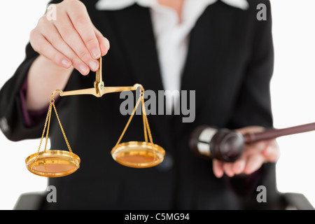 Junge Frau Holding Waage der Gerechtigkeit und eines Hammers mit der Kamera konzentrieren sich auf die Waage Stockfoto