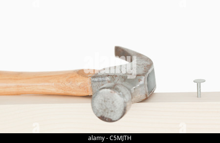 Einen Hammer und einen drived Nagel auf einem Holzbrett Stockfoto