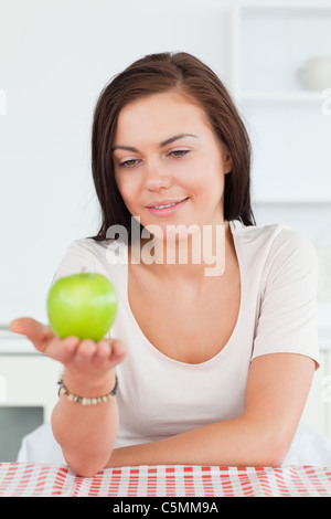 Lächelnde Brünette zeigt einen Apfel Stockfoto