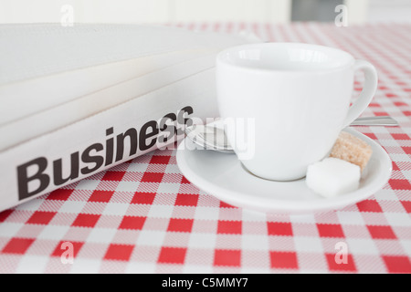 Eine Tasse Tee und eine Zeitung auf einer Tischdecke Stockfoto