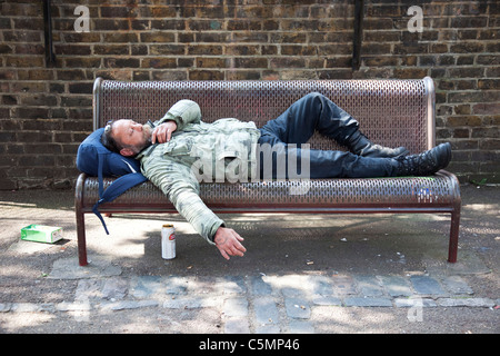 Mann (möglicherweise Obdachlose / Straße Trinker) schlafen auf einer Bank in East London. Stockfoto