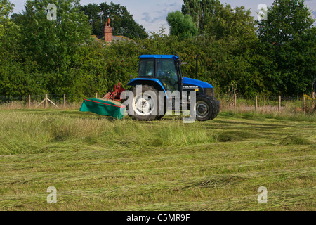 Mähen Heu mit einem New Holland TS90 4WD Trommel Traktor & eine Kverneland Taarup 1116 Mäher Stockfoto