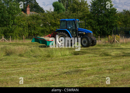 Mähen Heu mit einem New Holland TS90 4WD Trommel Traktor & eine Kverneland Taarup 1116 Mäher Stockfoto