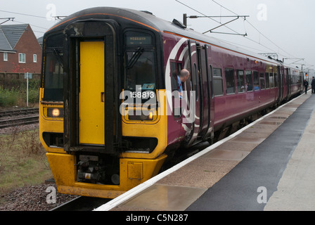 East Midlands Züge (EMT) Zug 158813 158-Klasse in Grantham Bahnhof auf Weg nach Norwich mit Fahrer aus Fenster gelehnt Stockfoto