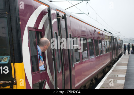 East Midlands Züge (EMT) Zug 158813 158-Klasse in Grantham Bahnhof auf Weg nach Norwich mit Fahrer aus Fenster gelehnt Stockfoto