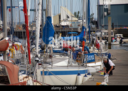 Hafenmeister sammelt die Gebühren für das Anlegen und kniet im Juni auf dem Ponton am Lymington Quay Harbour, Lymington, Hampshire UK Stockfoto