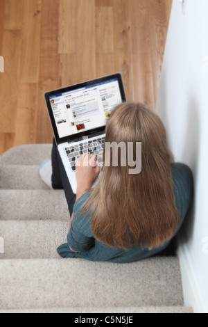 Junges Mädchen mit Laptop auf Facebook-Seite. Stockfoto