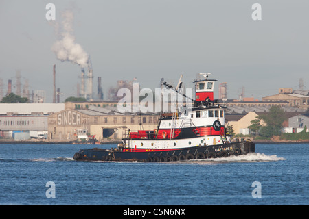 Norfolk Tug Schlepper "Kapitän D' mit der Singer Sewing Machine Factory im Hintergrund an der Newark Bay. Stockfoto