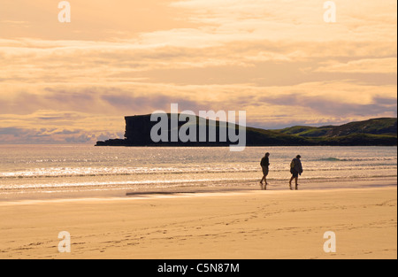Ein paar schlendert barfuß entlang des Wassers bei oldshoremore Strand, abends, in der Nähe von Kinlochbervie, Sutherland, Schottland, UK Stockfoto