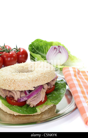 Bagel mit Thunfisch, Tomaten, Zwiebeln und Salat auf weißem Hintergrund Stockfoto