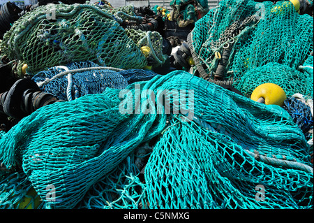 Haufen bunter Schleppnetzfischerei Fischernetze und schwimmt auf dem Kai am Hafen von Guilvinec, Finistère, Bretagne, Frankreich Stockfoto