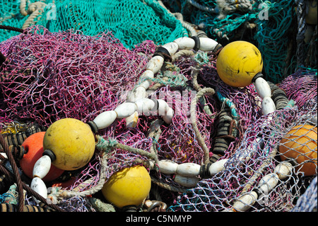 Haufen bunter Schleppnetzfischerei Fischernetze und schwimmt auf dem Kai am Hafen von Guilvinec, Finistère, Bretagne, Frankreich Stockfoto