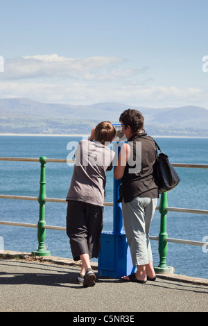 Frau und junge auf der Suche nach Delfinen, die mit einer Eule Teleskop über Cardigan Bay. Criccieth Lleyn Halbinsel Gwynedd North Wales UK. Stockfoto