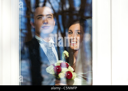 Brautpaar steht am Fenster auf ihre Hochzeit und suchen außerhalb Stockfoto