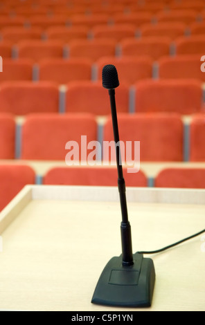 Schwarz Mikrofon steht gegen Auditorium mit roten Stühlen Stockfoto