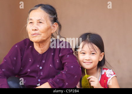 Ein vietnamesisches Kind sitzt mit ihrer Großmutter in Duong Lam Dorf, Vietnam Stockfoto