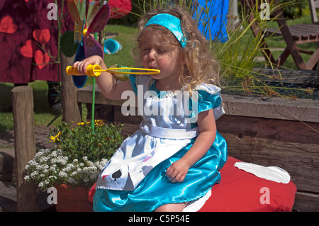 Kleines Mädchen, gekleidet In Alice im Wunderland Kostüm Seifenblasen Stockfoto