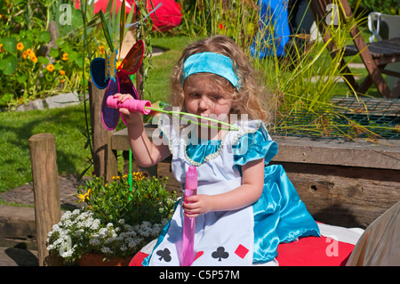 Kleines Mädchen, gekleidet In Alice im Wunderland Kostüm Seifenblasen Stockfoto