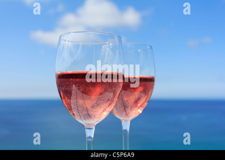 Brille von Roséwein durch den Ozean Stockfoto